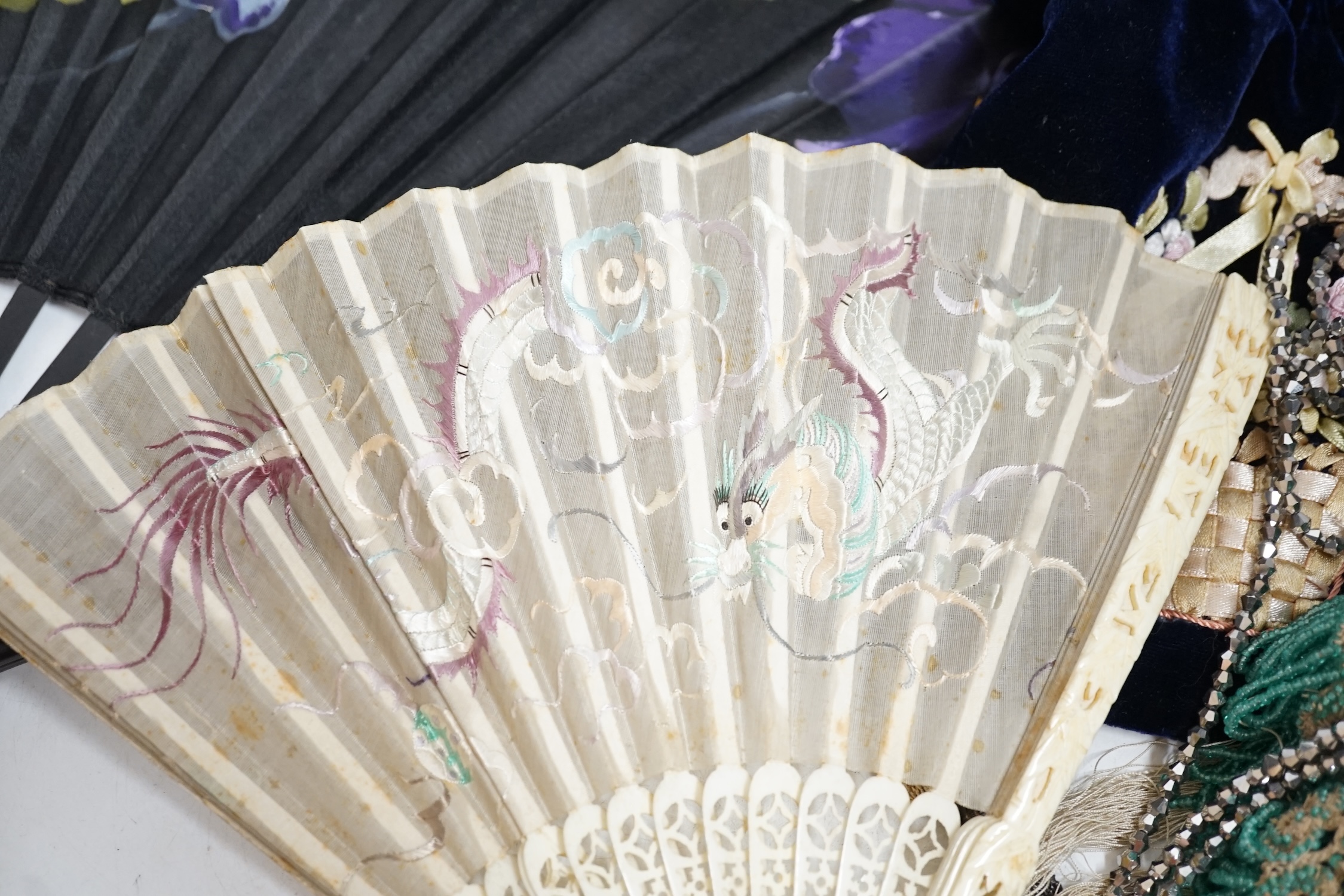 A Chinese 1920’s boxed carved bone and silk embroidered dragon fan, a larger European pansy decorated fan, a bead worked basket, a mat, two cut steel necklaces, an embroidered pin cushion, an evening bag and a misers pur